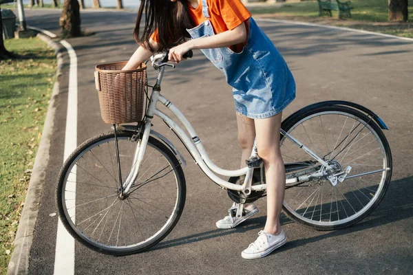 公園内の女性の足の間の白い自転車の作物のイメージ — ストック写真