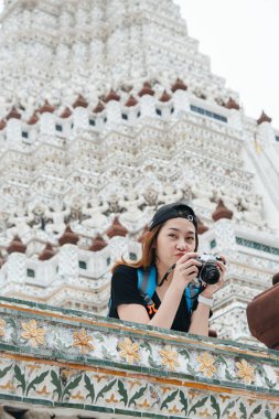 Wat Arun 'daki Asyalı sırt çantalı kadın tapınağın fotoğrafını çekmekten zevk alıyor..