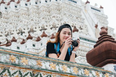 Wat Arun 'daki Asyalı sırt çantalı kadın tapınağın fotoğrafını çekmekten zevk alıyor..