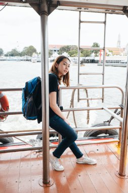 Sırt çantalı kadın Chao Praya nehrinde tekneyle seyahat ediyor..