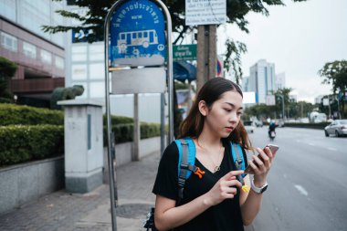 Bangkok 'ta gezen Asyalı güzel bir bayan sırt çantalı. Akıllı telefon kullanan kadın GPS uygulamasını takip et.