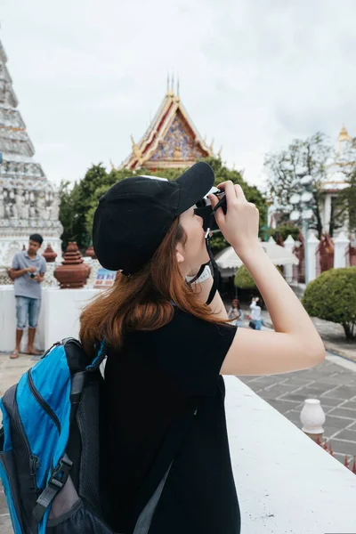 亚洲背包客妇女在Wat Arun用相机拍照的侧视图 — 图库照片
