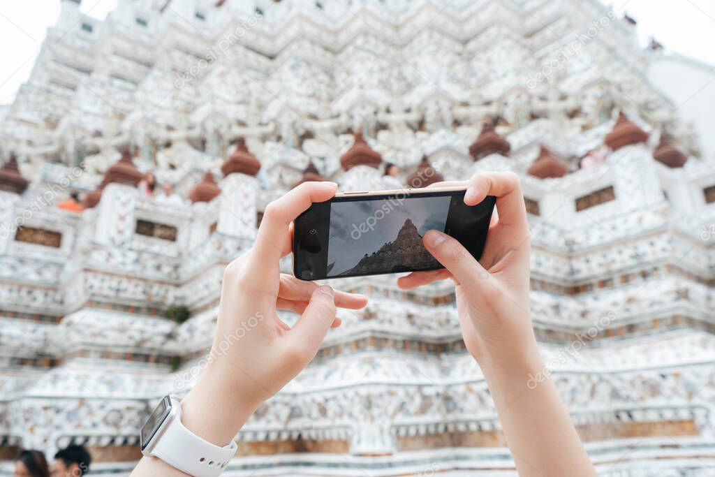 Hand of woman taking picture with smartphone at thai temple wat arun.