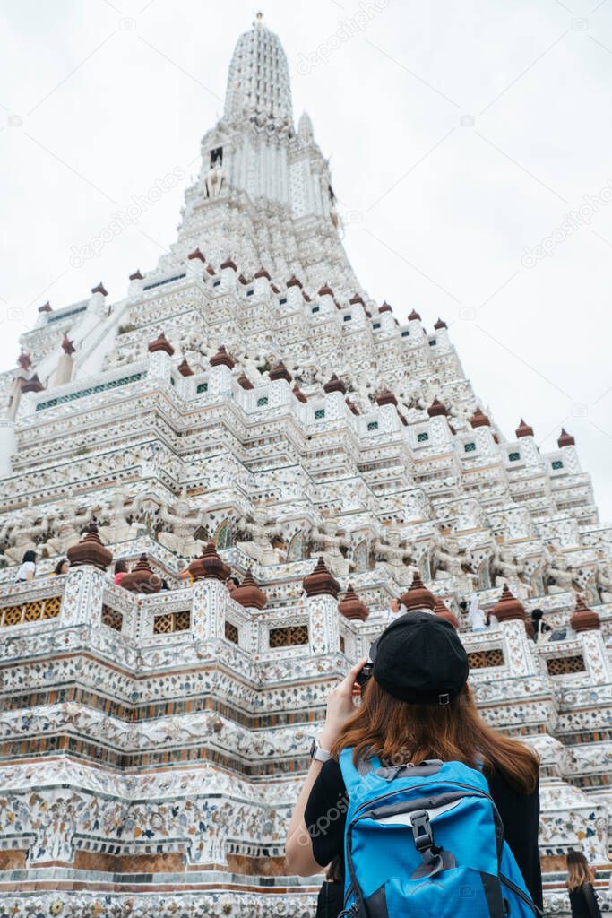 Back view of asian backpacker woman taking picture of temple.