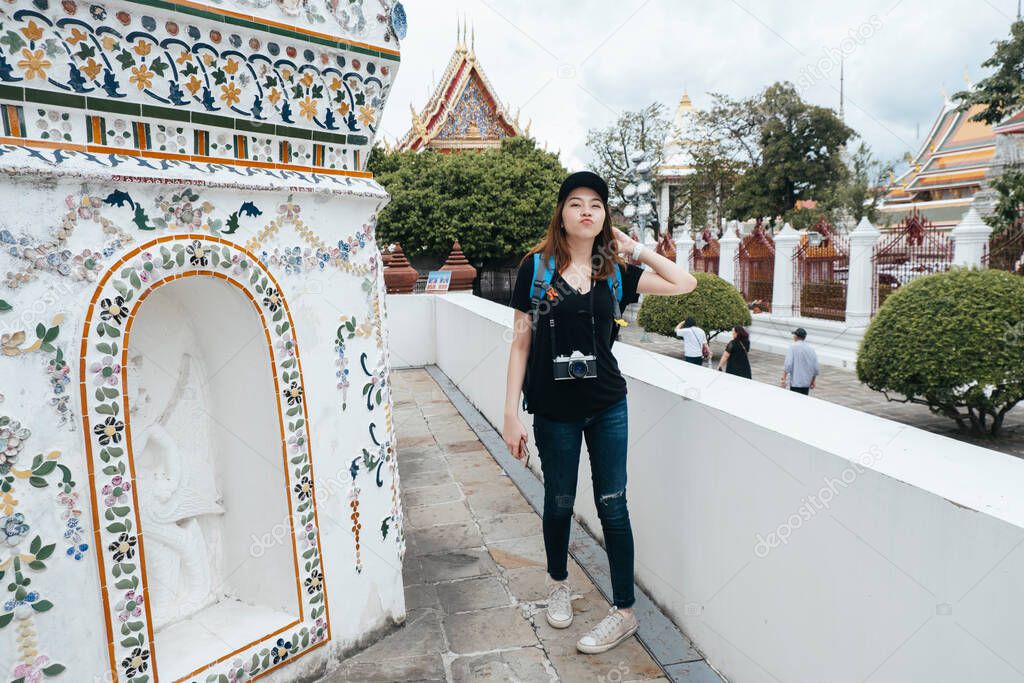 Portrait of young asian backpacker woman enjoy sightseeing inside wat arun temple palace.
