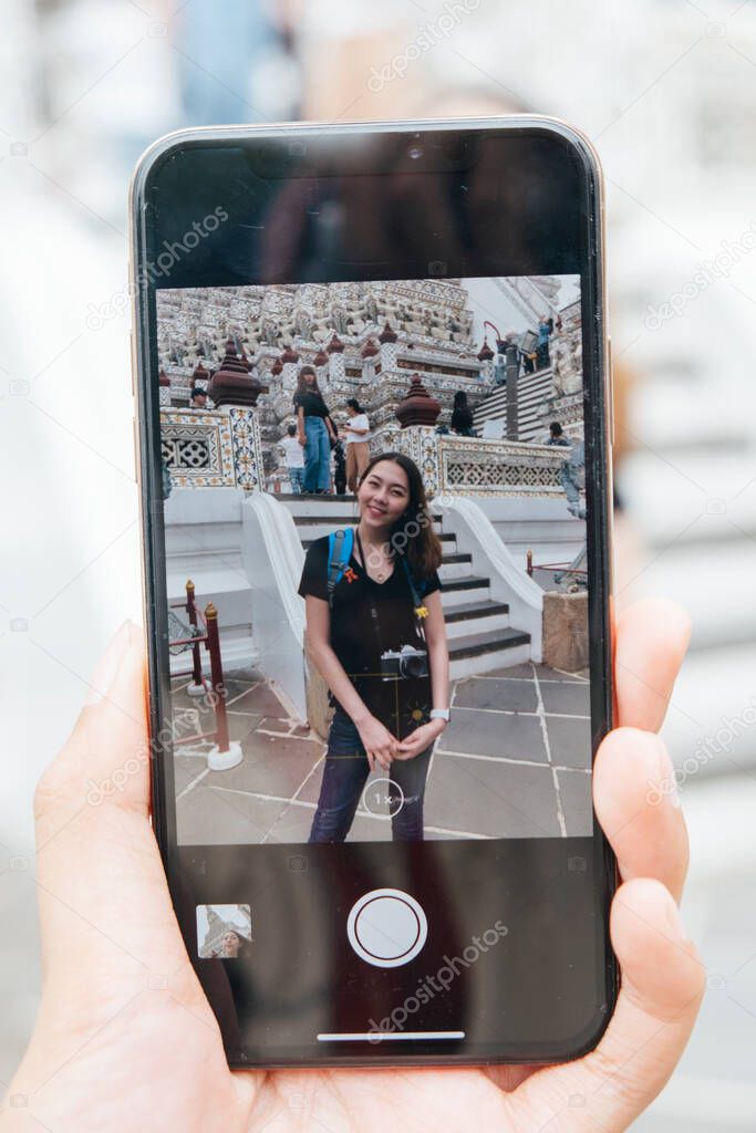 Hand of woman in smartphone travel at wat arun.