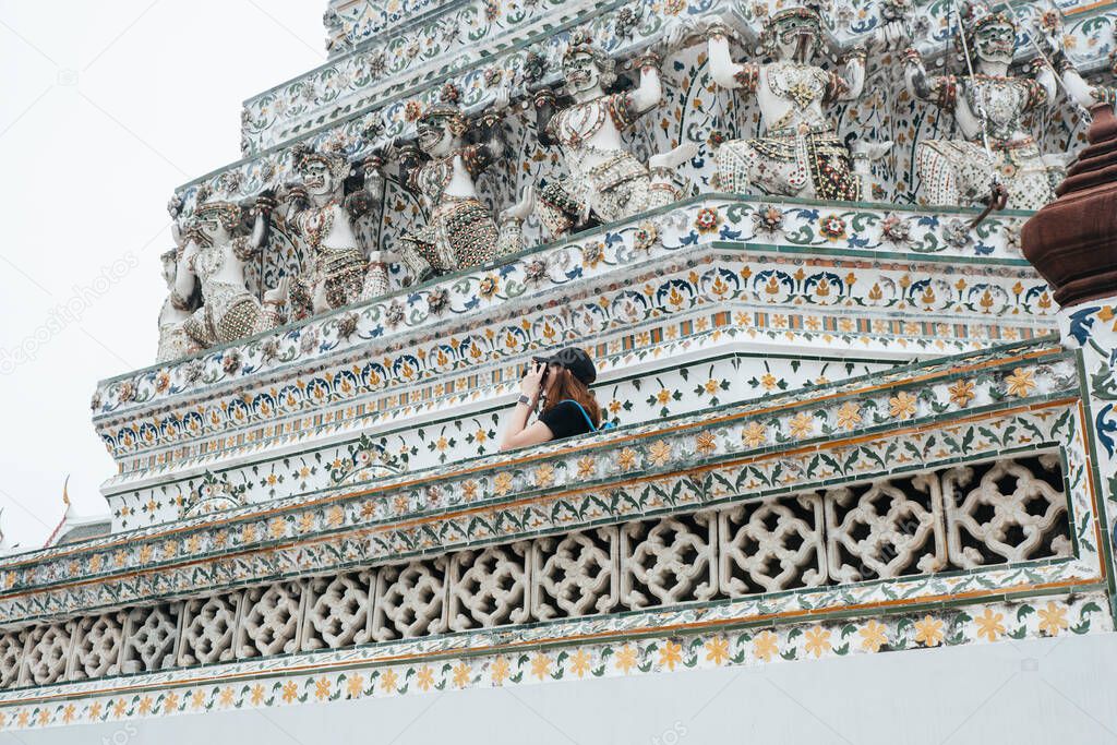 Asian backpacker woman in wat arun enjoy taking photo of the temple.