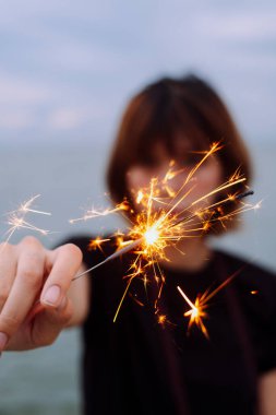 Genç Asyalı kısa saçlı kadının plajda maytapla oynayan portresi..