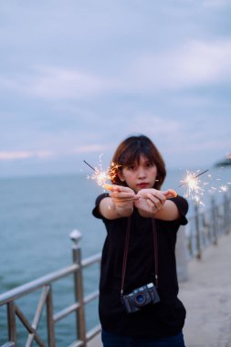 Genç Asyalı kısa saçlı kadının portresi sahilde iki maytapla oynuyordu..