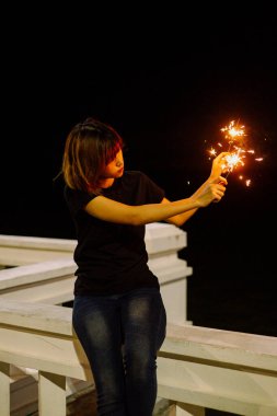 Genç Asyalı Taylandlı kadın geceleri maytapla oynuyor..