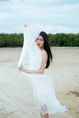 Açık havada beyaz peçeli Asyalı uzun siyah saçlı bir kadının portresi..