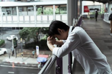 Üzücü iş adamı üst geçit tırabzanına yaslanıyor. Umutsuz bir iş adamı üst geçidin altındaki yola bakıyor. İşi bıraktıktan sonra hayatını düşünen düşünceli bir işadamı..