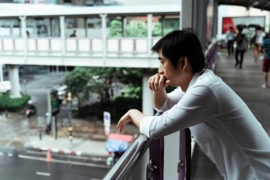Üzücü iş adamı üst geçit tırabzanına yaslanıyor. Umutsuz bir iş adamı üst geçidin altındaki yola bakıyor. İşi bıraktıktan sonra hayatını düşünen düşünceli bir işadamı..