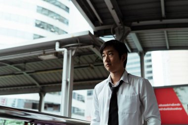 Asyalı iş adamı depresyonda üstgeçitte yürüyor..