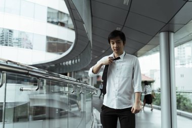 Asyalı işadamı işten ayrıldıktan sonra tişörtten kravat çekiyor. Bu iş için yeterli..