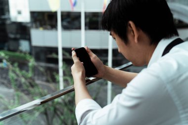 Şehirdeki tırabzanlar üzerinde cep telefonu kullanan Asyalı iş adamı..