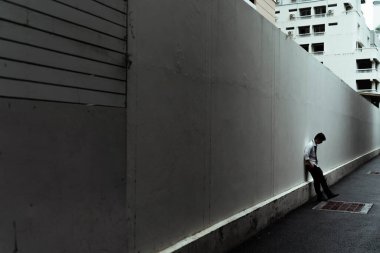 Kasvetli karanlık sokakta duvarın karşısında duran üzgün işadamı..