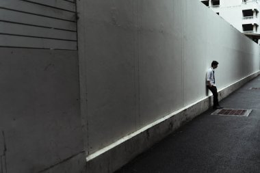 Kasvetli karanlık sokakta duvarın karşısında duran üzgün işadamı..