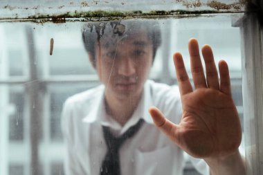 Üzgün Asyalı işportacı şeffaflık camına elini koydu. Umutsuz görünüyordu. Bulanık arkaplan.