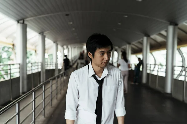 Sad businessman lost his mind after losing his job wandering on walkway in Bangkok. Serious businessman standing on overpass after quiting job.