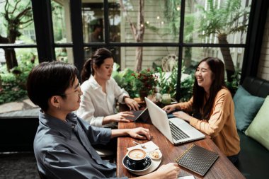 Girişimci genç iş adamları birlikte çalışıyor ve tartışıyorlar. Kafede planlama ve beyin fırtınası yapan genç iş adamları. Takım çalışması konsepti.