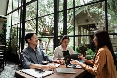 Girişimci genç iş adamları birlikte çalışıyor ve tartışıyorlar. Kafede planlama ve beyin fırtınası yapan genç iş adamları. Takım çalışması konsepti.