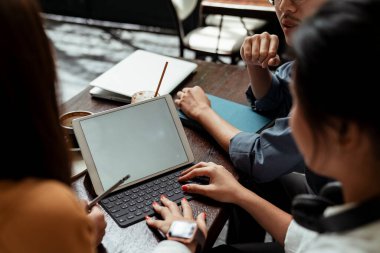 Üç genç iş adamı birlikte tablet üzerinde çalışıyorlar..