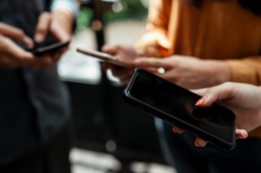 Bir grup insan cep telefonu beyazını birlikte kullanıyor ve ona bakıyor. Akıllı telefon oynayanların el kameralarını kapat.