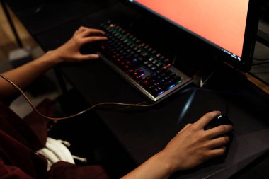 Bilgisayarda fare ve klavyeyle oyun oynayan oyuncunun elleri.