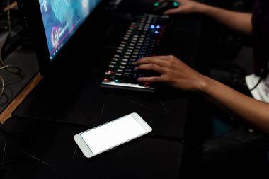 Oyuncuların elleri klavyede daktilo çalıyor. Akıllı telefondaki boş ekran klavyeye yakınlaştırılıyor.