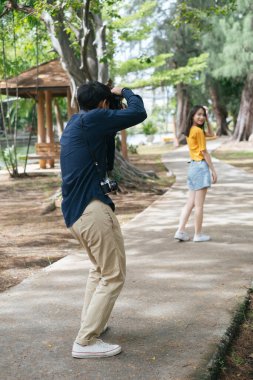 Fotoğrafçı, parkta yürürken genç bir kızın fotoğrafını çekiyor..