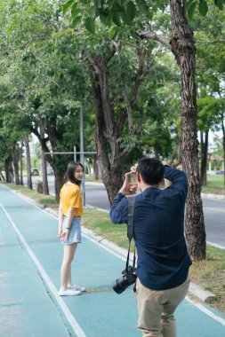 Bisiklet yolundaki bir kızın fotoğrafını çekmeden önce erkek fotoğrafçı elleriyle çerçeveletiyor..