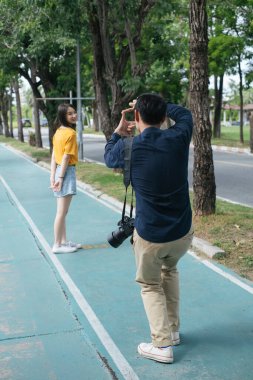 Bisiklet yolundaki bir kızın fotoğrafını çekmeden önce erkek fotoğrafçı elleriyle çerçeveletiyor..