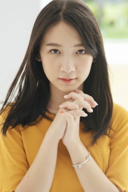 Sarı tişörtlü siyah uzun saçlı kız ellerini göğsünden tutarak büyülüyor..