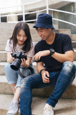 Fotoğrafçı ve model işlerini bitirdikten sonra kaldırım taşından merdivenlerde oturuyor ve dijital kameradaki fotoğrafı kontrol ediyor..
