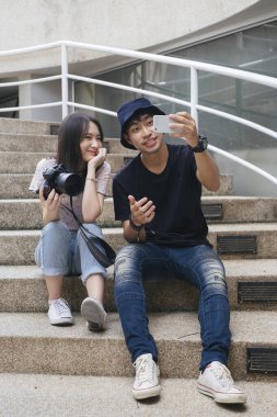 Çekimler bittikten sonra kaldırım taşı merdivenlerde otururken fotoğrafçı ve manken birlikte selfie çekiyorlar..