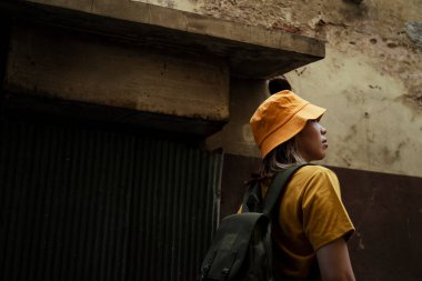 Sarı tişörtlü sırt çantalı kız gezintisinde eski şehirde dolanıyor..