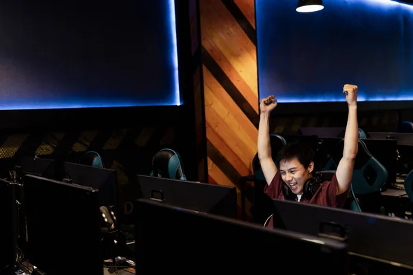 Professional Gamer Playing and Winning the game, raising hands after winning the game match at internet cafe.