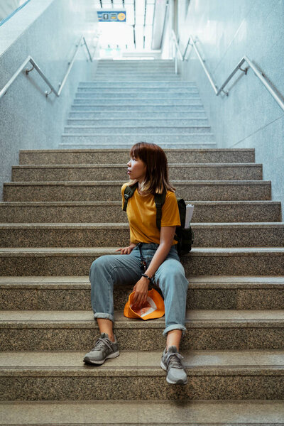 Желтый рюкзак женщины с зеленым рюкзаком стоит в конце вагона метро.