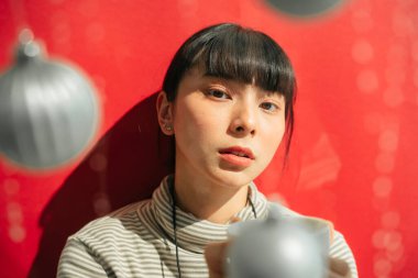 Kapalı portre - Güzel Asyalı Taylandlı uzun siyah saçlı kadın kırmızı arka planda kahve fincanı tutuyor.