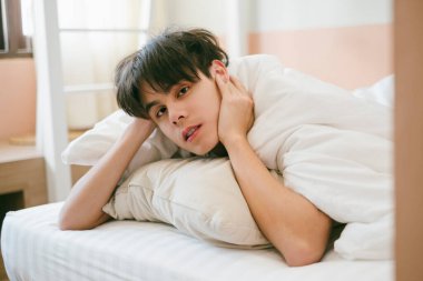 Siyah saçlı adam karın üstü yatar ve yatarken boynunu tutar..