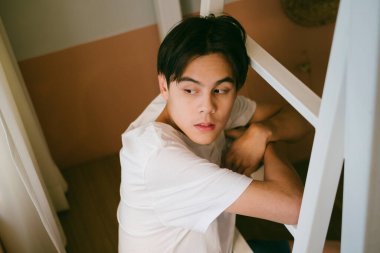 Beyaz tişörtlü siyah adam merdivene sarıldı ve pencereden dışarı baktı..