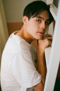 Beyaz tişörtlü siyah adam merdivene otur merdiveni tut ve yüzünü sağa çevir..