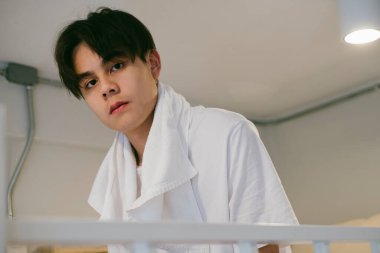 Duş aldıktan sonra boynunda beyaz havlu olan bir adamın portresi..