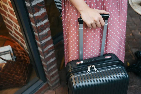 Woman in pink dress with travel luggage bag on street. Travel concept.