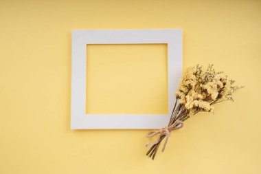 Parlak arkaplandaki sarı çiçekli beyaz kağıdı taklit et. Üst görünüm.