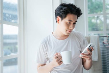 Beyaz tişörtlü bir adam konuşmayı bitirdikten sonra telefonu kapatıyor..