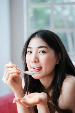 Tatlı dalgalı uzun saçlı kız kahvaltıda dudağındaki yoğurdu temizlemek için dudağını yalıyor..