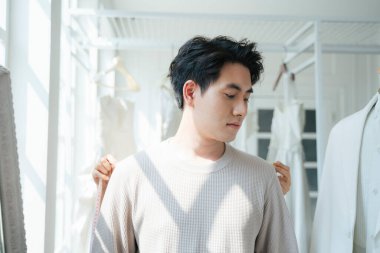 Bir adam gelinlik seçmek için düğün stüdyosunu ziyaret eder ve dener, bir personel elbisesi için omuzlarını ve kollarını ölçer..