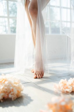 Gelinin gölgelerinin kırpılmış görüntüsü beyaz peçeyle duruyor güneş ışığında pencereden içeri doğru..